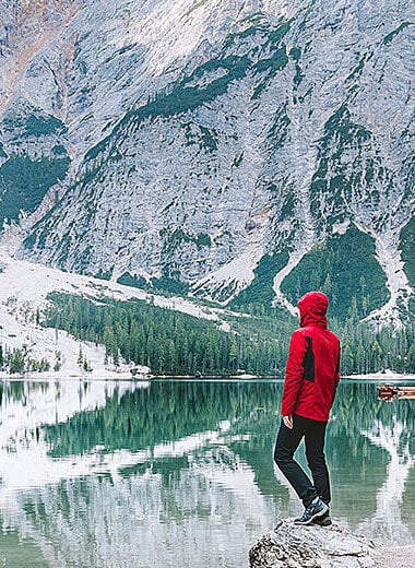 A man in a red coat in the snowy mountain walking across a lake Développeur freelance Lille