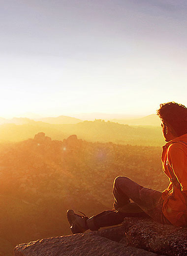 A man in a red coat watching the sunset on top on a mountain, Développeur freelance Lille